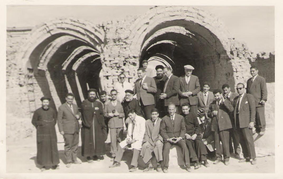 About twenty men, some in clerical robes and most in suits, gathered before tall mud-brick arches
